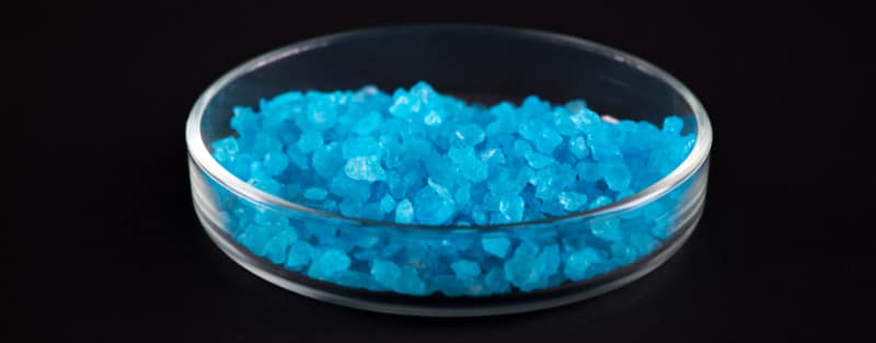 Blue crystals in a petri dish, showcasing the synthetic drug compounds in a laboratory setting.