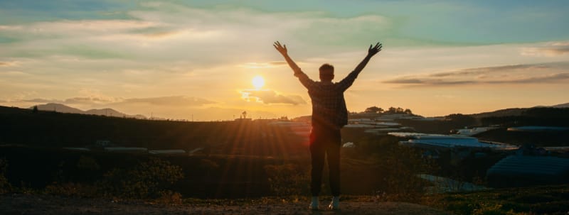 A man leaping energetically into the air against a backdrop of a beautiful sunset, representing the triumph and hope that can be achieved in overcoming drug withdrawals and embracing a new beginning.