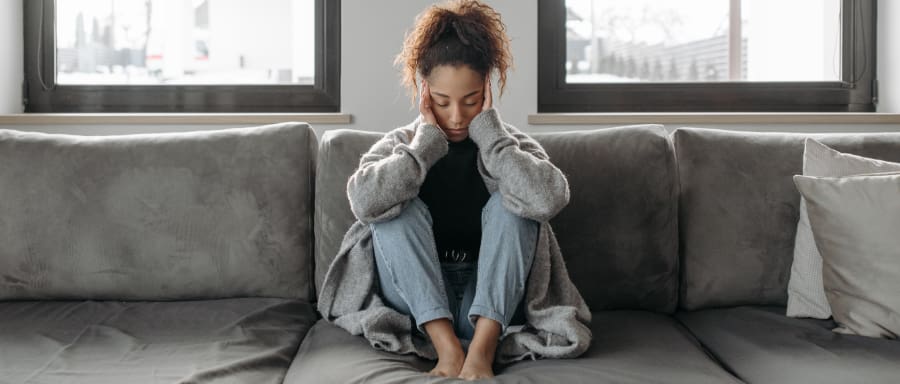 Woman on a couch with her head in her hands, reflecting the emotional struggles of alcohol withdrawal and the need for support during recovery.