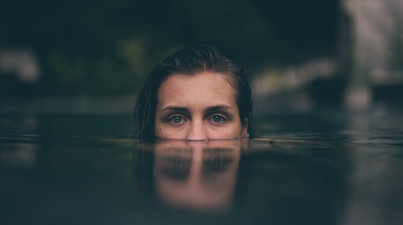 A woman's eyes peek above the waterline, symbolizing the danger and risk of mixing stimulants and depressants