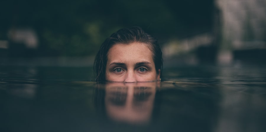 A woman's eyes peek above the waterline, symbolizing the danger and risk of mixing stimulants and depressants