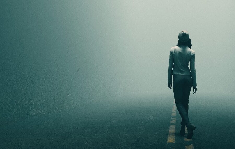 A woman pondering the uncertain journey ahead, representing the effects of drug abuse, as she gazes down a fog-covered road.