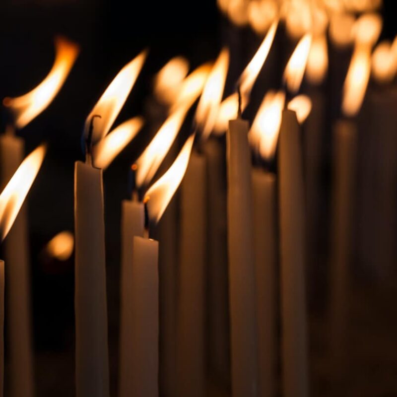 Numerous candles standing steadfast against a blowing wind, metaphorically illustrating the enduring strength and resilience required in the journey of inpatient detox rehab, despite the challenges faced