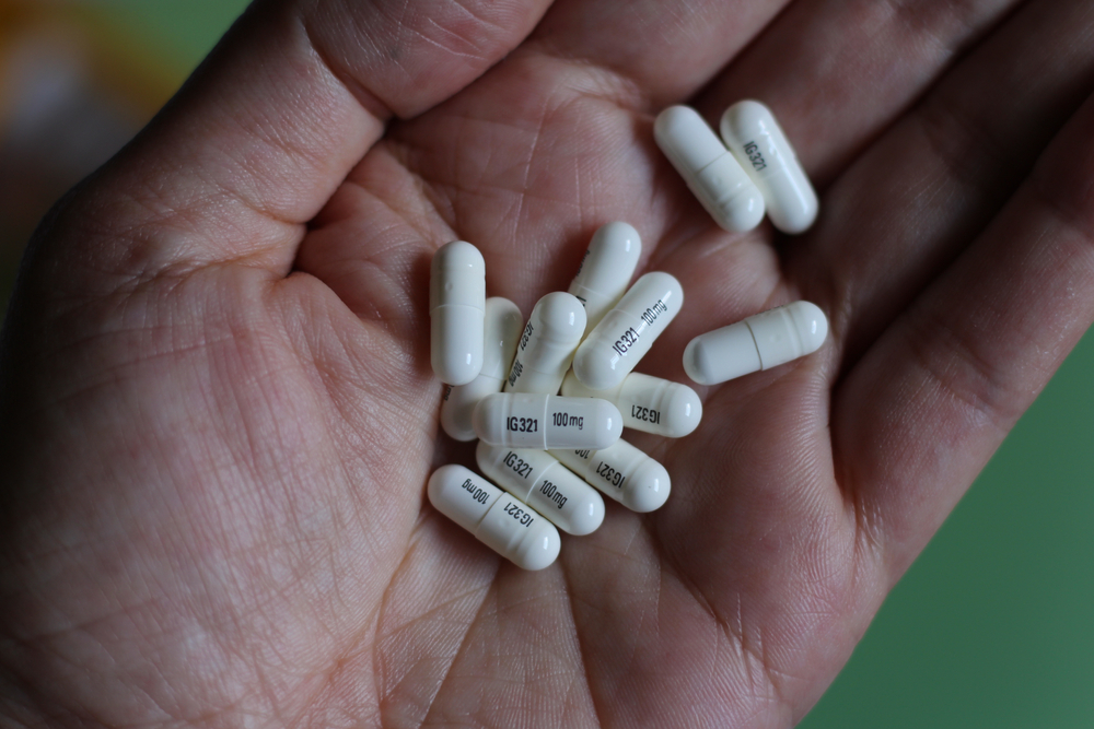 Closeup of a hand with white gabapentin capsules