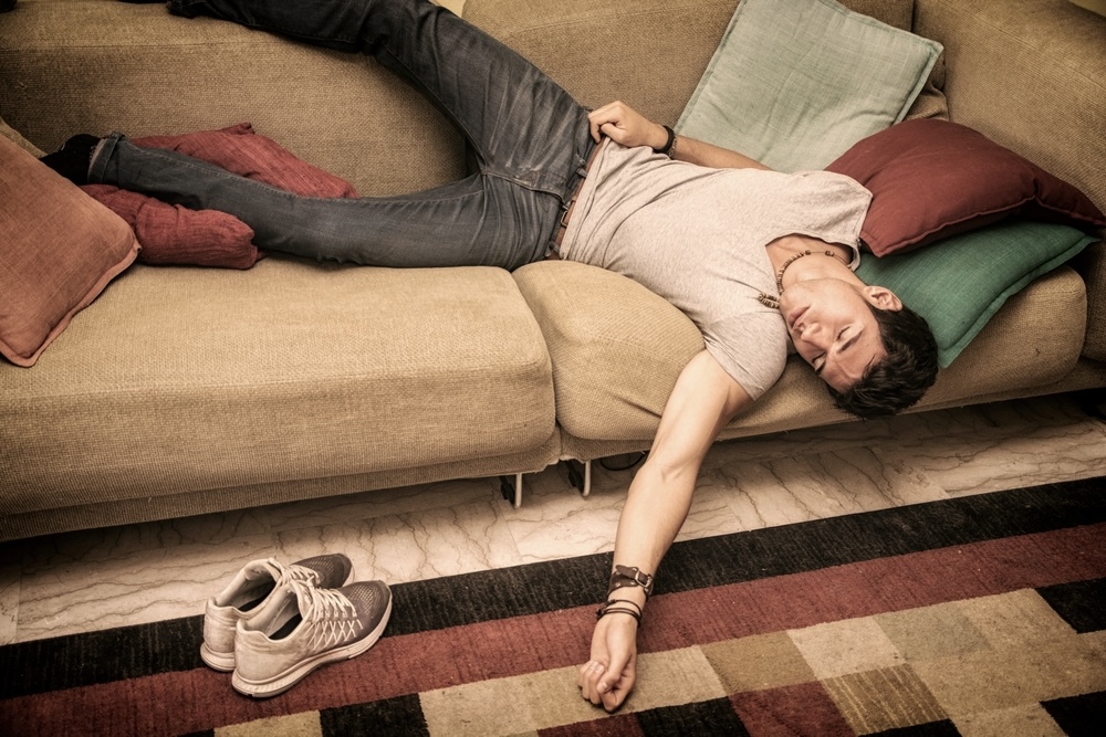 Man asleep on the couch from overdrinking alcohol