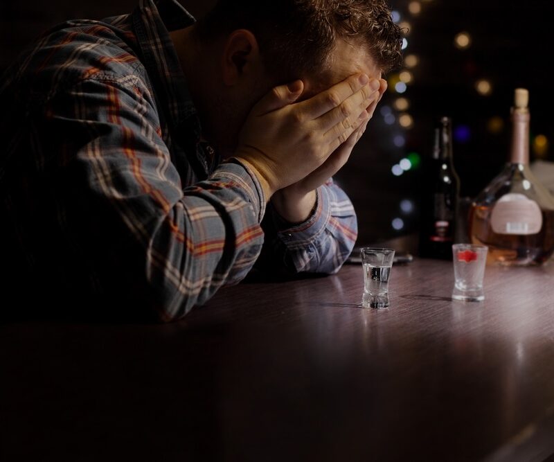 Man in a dimly lit bar dealing with alcohol addiction